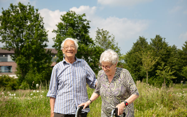 Seniorenzorg Philippus Neri lachend koppel senioren wandelend in de tuin