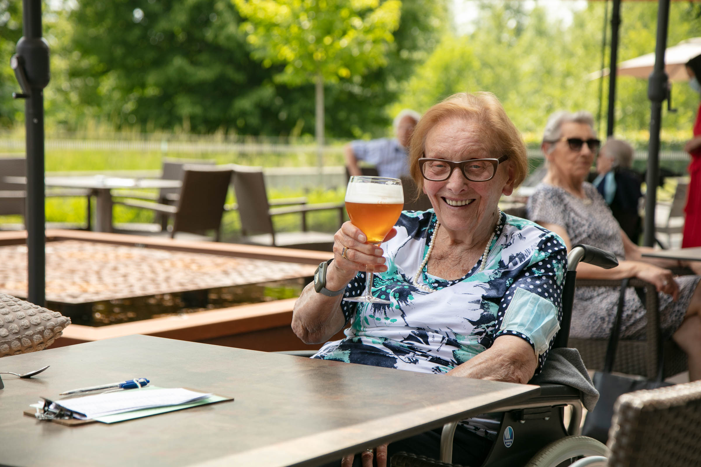 Seniorenzorg Philippus Neri vrolijke senior dame met pintje bier op terras