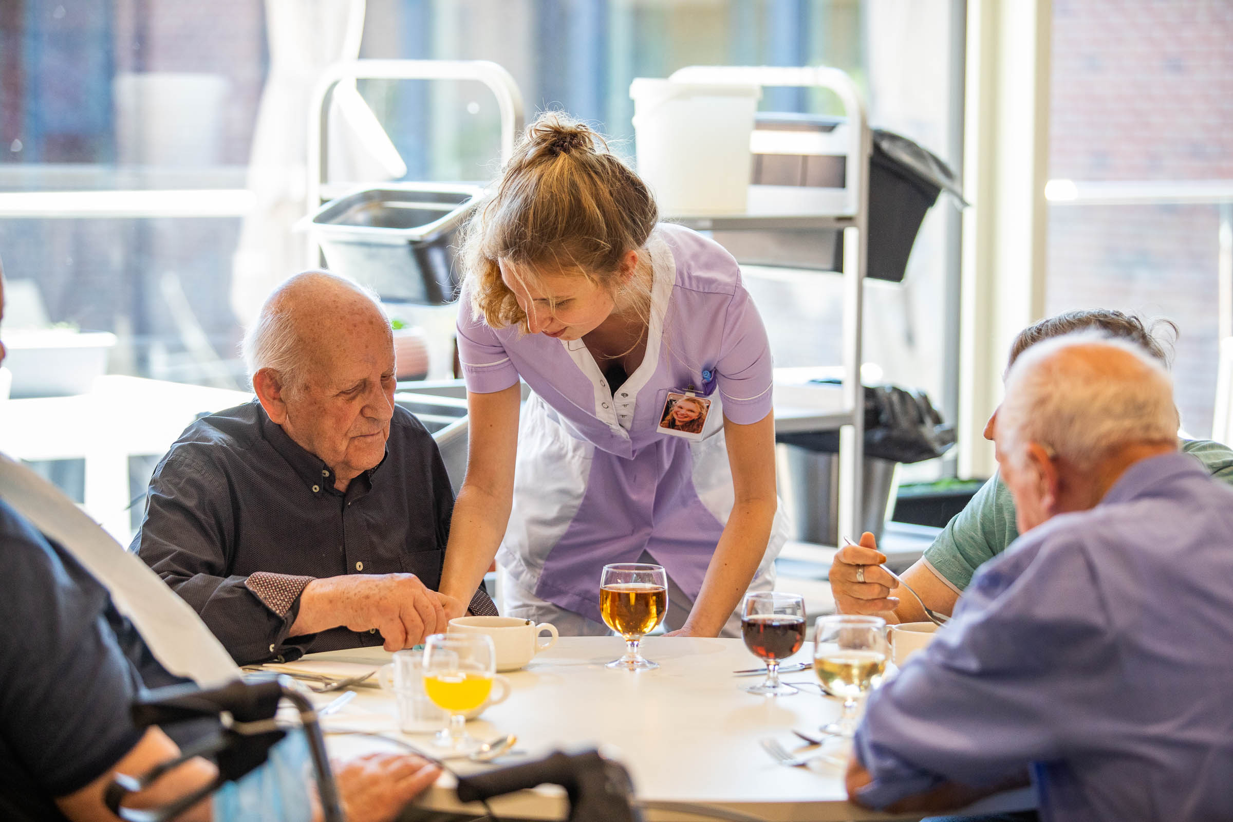 Seniorenzorg Philippus Neri zorgkundige bedient senior heer aan tafel in woonzorgcentrum Sint-Jozef